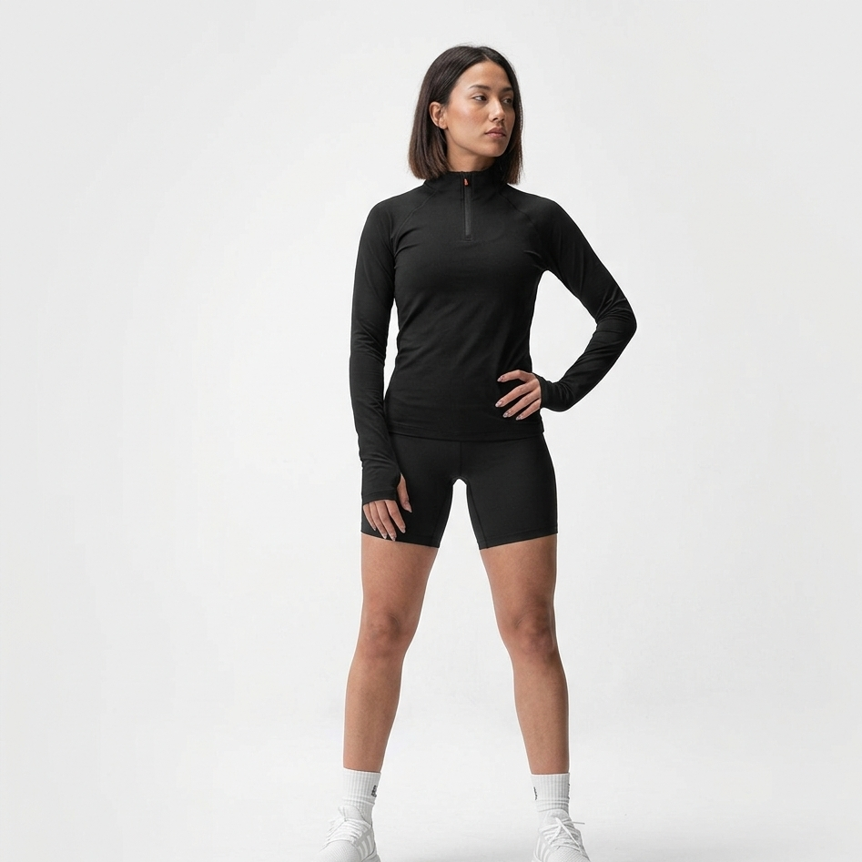 Person wearing a black long-sleeve top and black shorts on a white background