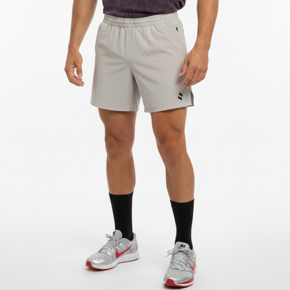 LIGHT BEIGE athletic shorts with an elastic waistband and a small black SOPRO logo on the lower left leg, displayed flat against a GREY background.