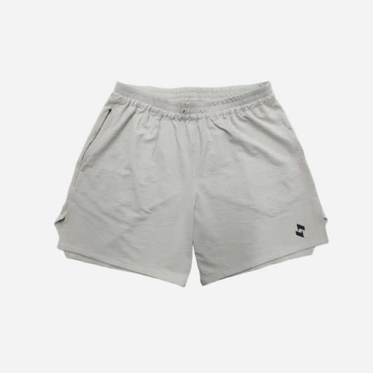 LIGHT BEIGE athletic shorts with an elastic waistband and a small black SOPRO logo on the lower left leg, displayed flat against a GREY background.