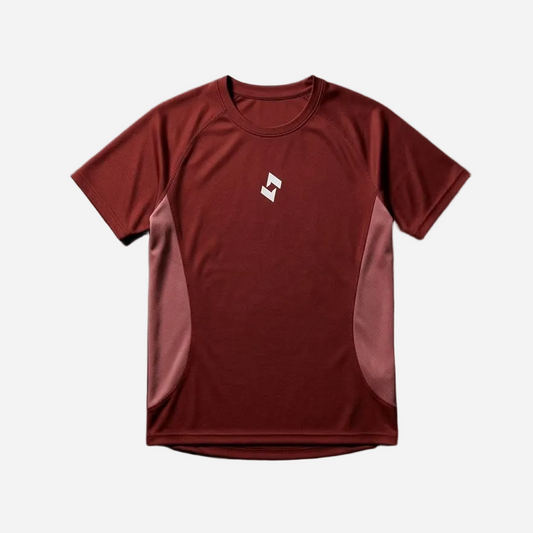 A short-sleeve athletic t-shirt in red with lighter dusty rose side panels and a small white geometric logo on the left chest, 